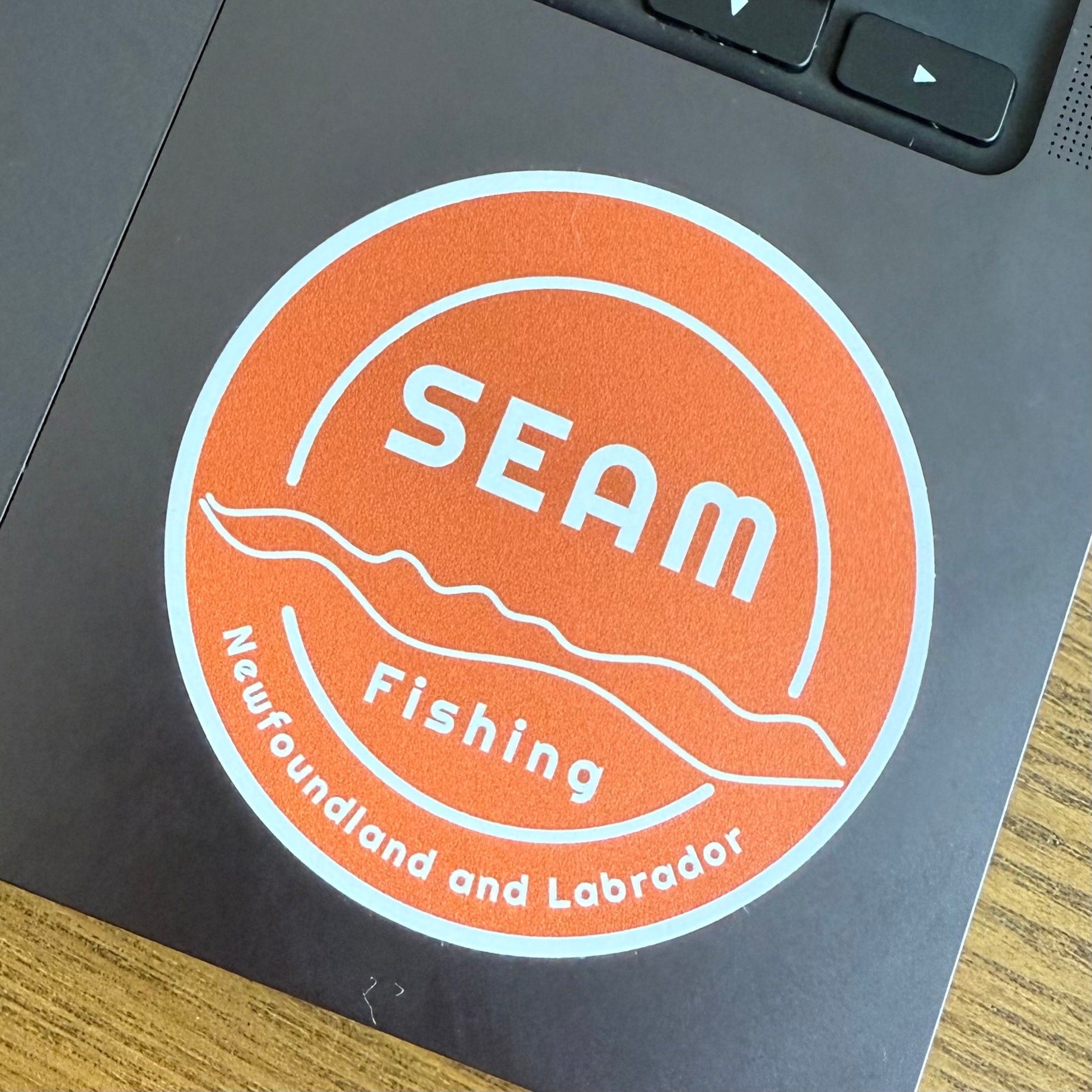 SEAM Fishing logo sticker on a laptop (global)