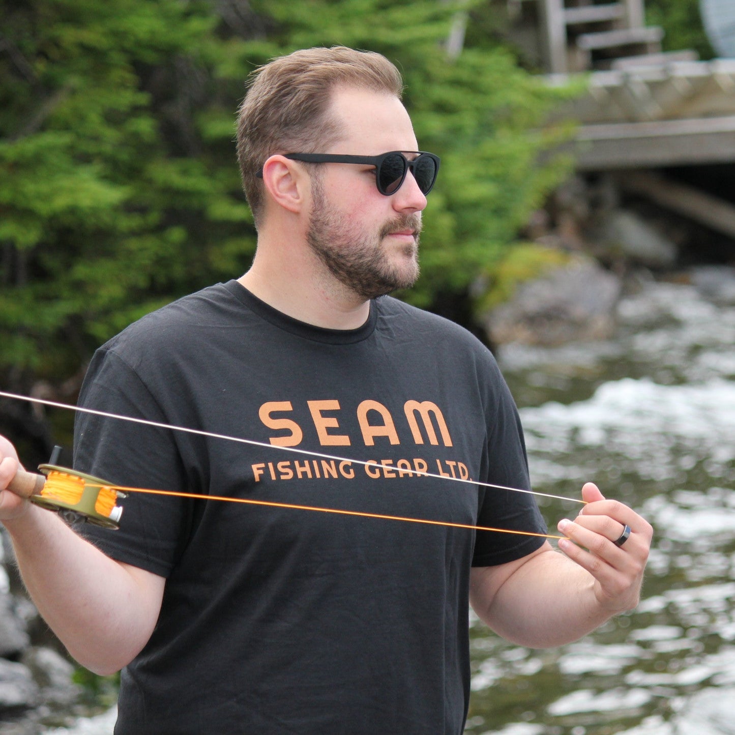 Man wearing a 'SEAM Fishing Gear Ltd' t-shirt fly fishing (global).
