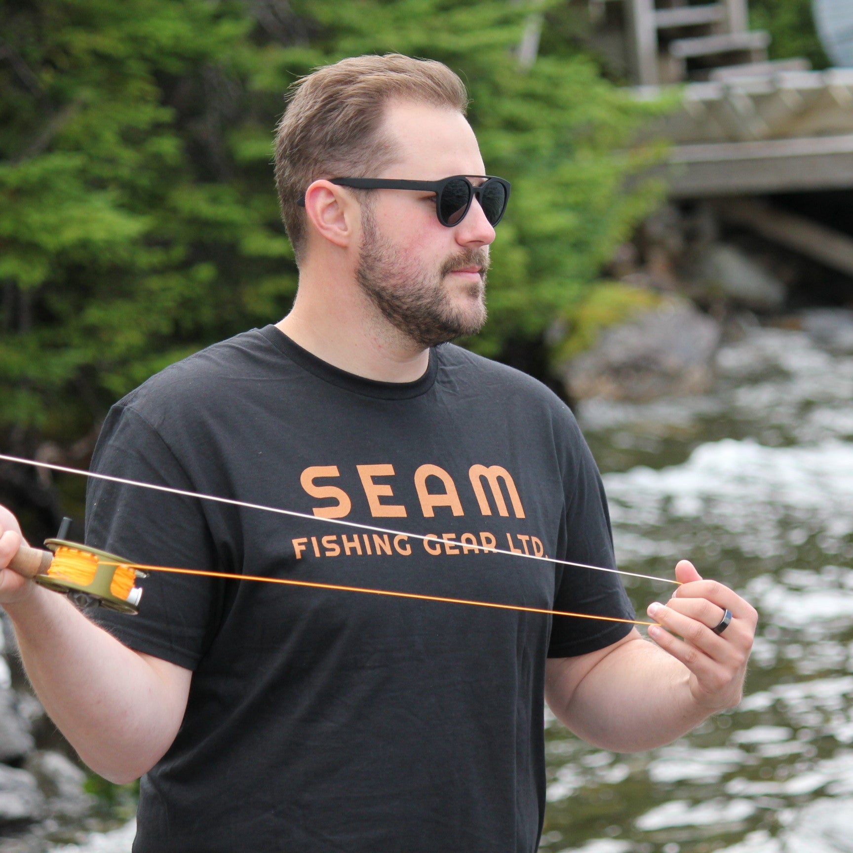 Man wearing a 'SEAM Fishing Gear Ltd' t-shirt fly fishing (global).